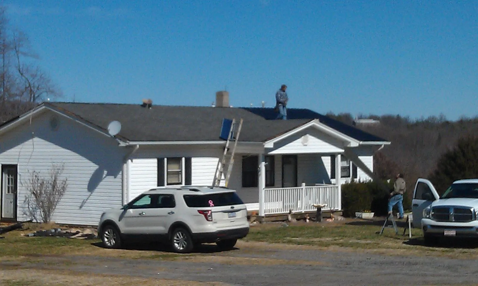 Roofers stripping shingles from a white ranch house roof in Westport